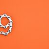 A metal chain shaped like the number nine against a vibrant orange background with copy space.