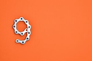 A metal chain shaped like the number nine against a vibrant orange background with copy space.