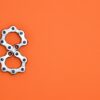 Creative arrangement of bicycle chain links in the shape of the number eight on a bright orange background.