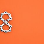 Creative arrangement of bicycle chain links in the shape of the number eight on a bright orange background.