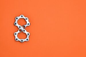 Creative arrangement of bicycle chain links in the shape of the number eight on a bright orange background.