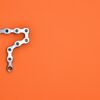 Artistic arrangement of bicycle chain shaped like number seven on orange background.