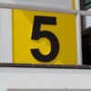 Close-up of the number five on a vivid yellow building facade. Modern design.