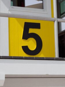 Close-up of the number five on a vivid yellow building facade. Modern design.