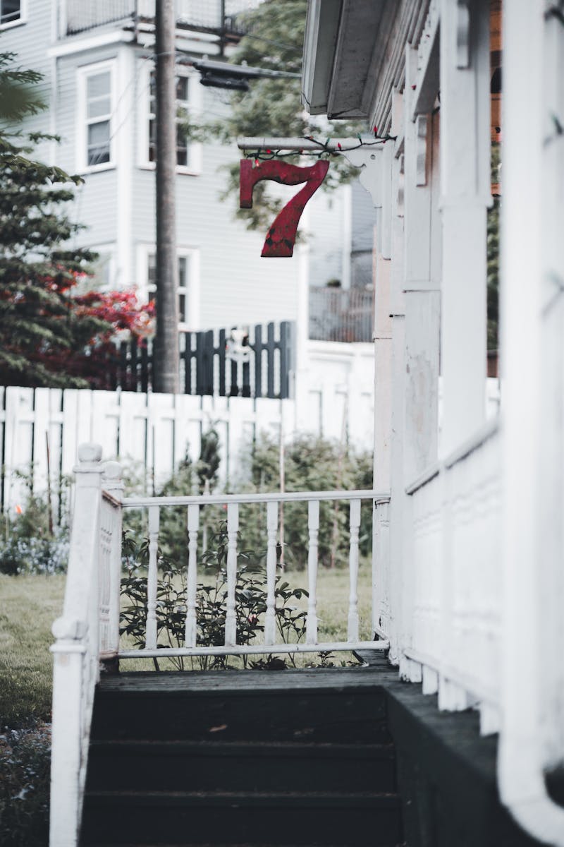 Front view of a house with vibrant red number 7 and white wooden railing.