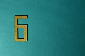 A golden number six on a teal background, perfect for decorative purposes.