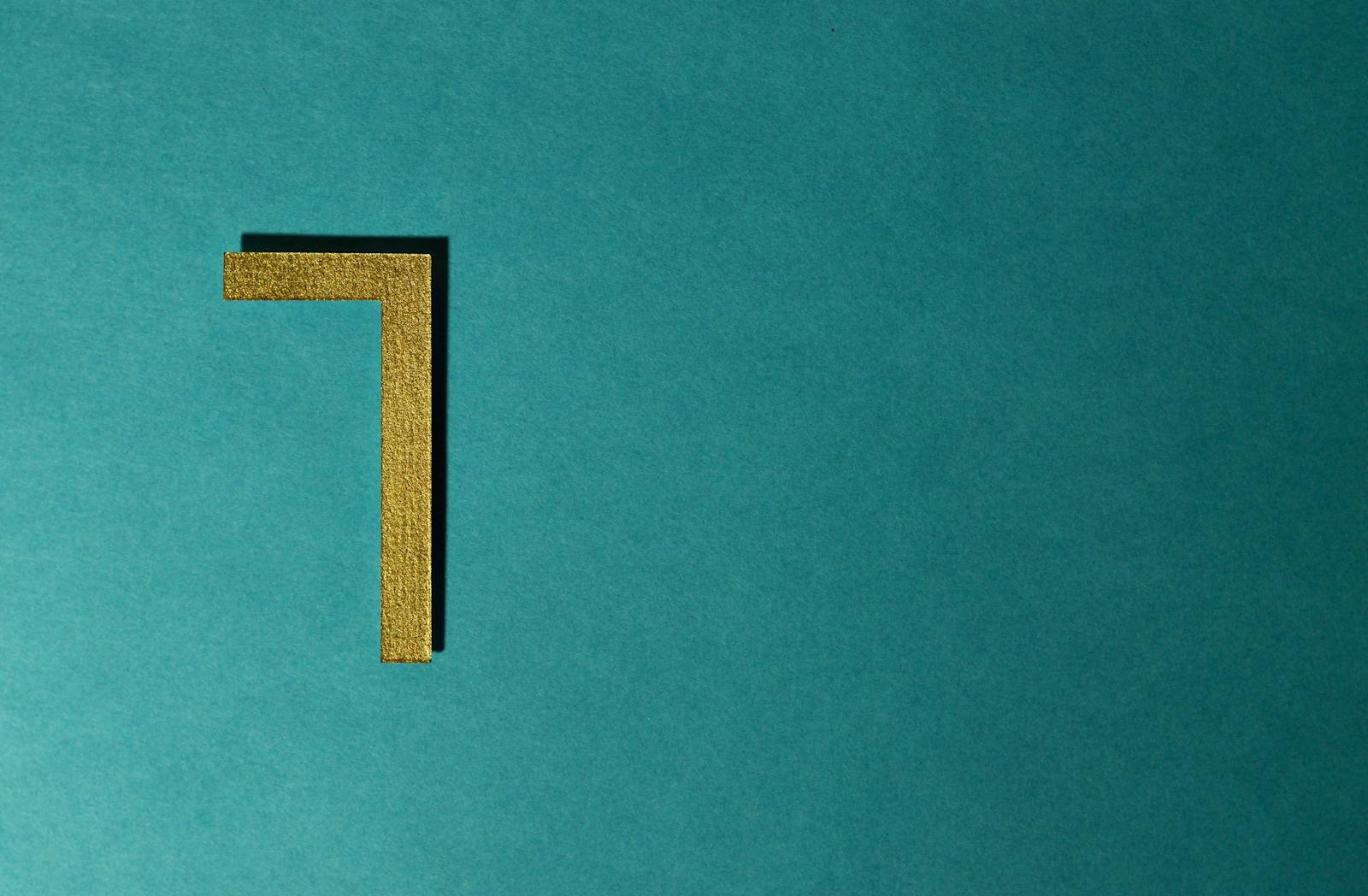 Minimalist image of a golden numeral seven on a teal background, ideal for decorative use.